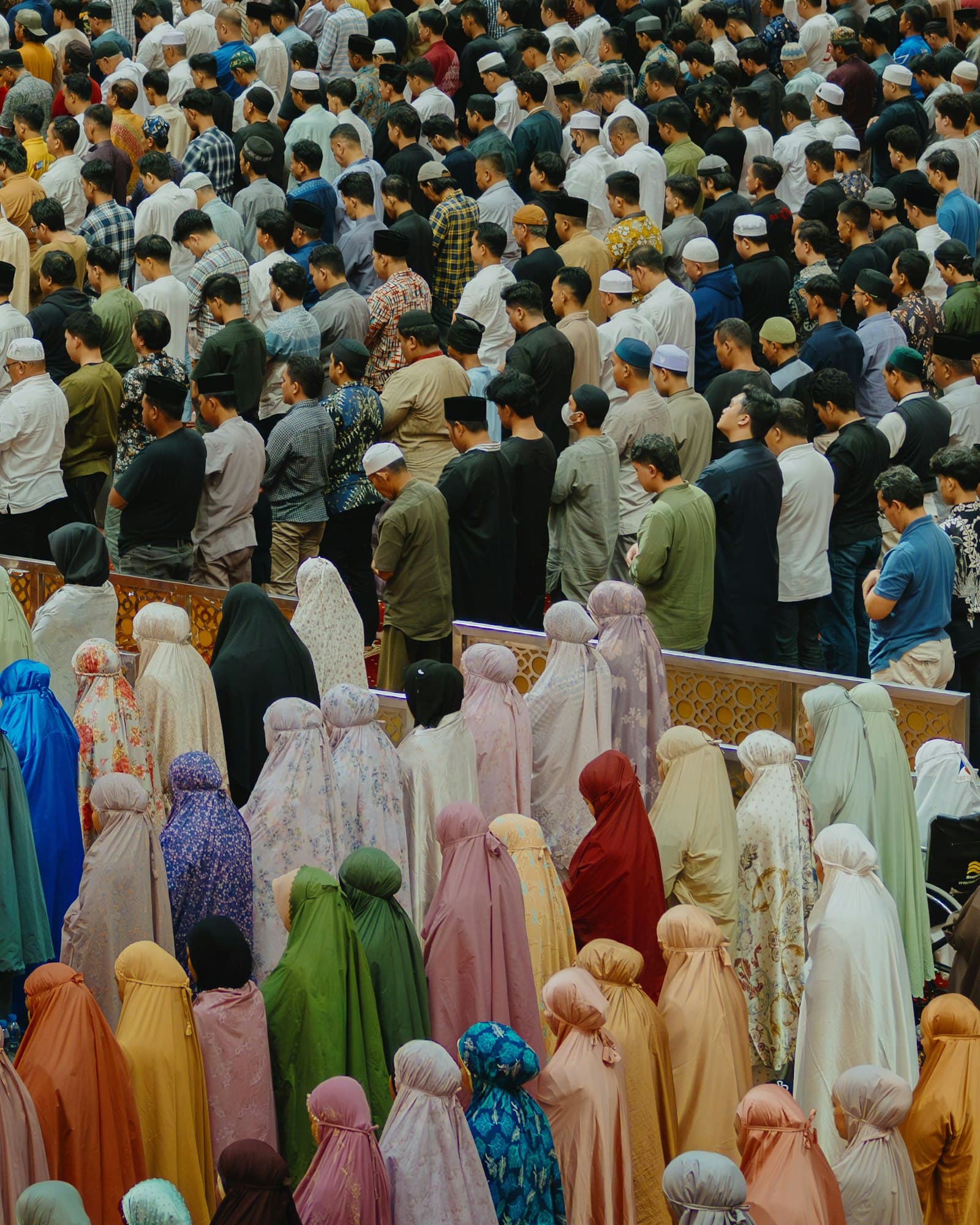 Congregation of men and women in telekung lined up for prayer